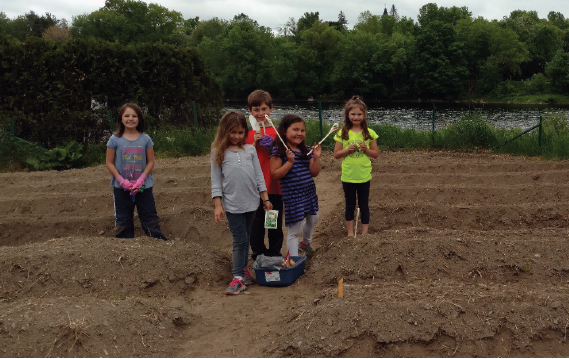 children smiling and tending to their vegetable garden