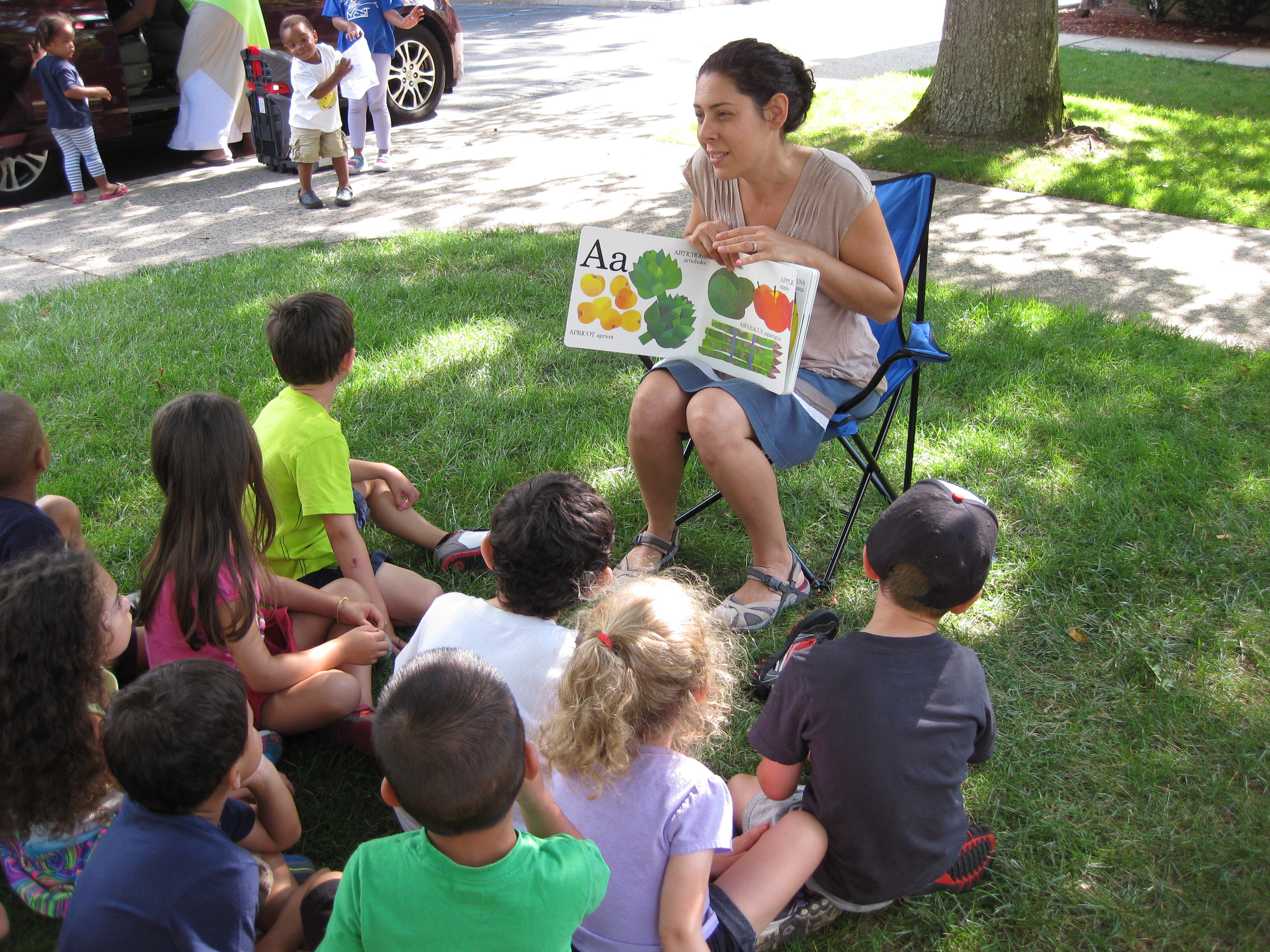 children sitting outside in grass watching a nutrition educator