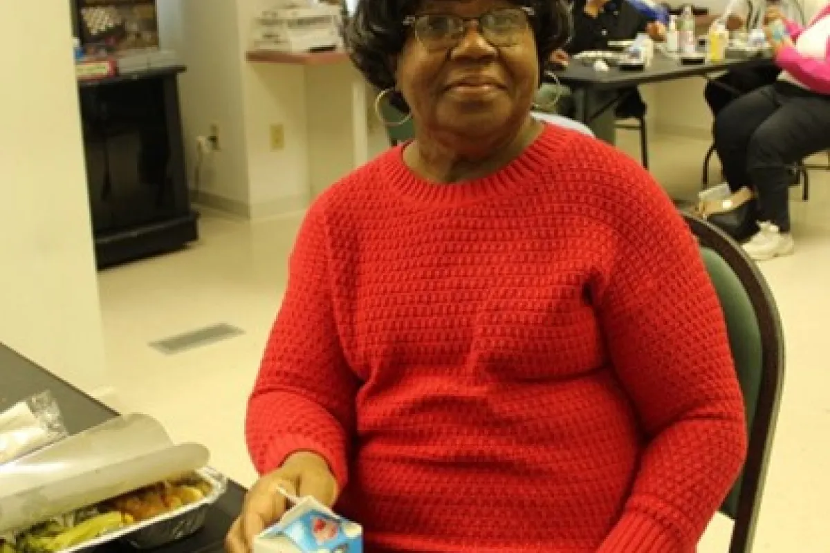A woman enjoing a meal at a community center.