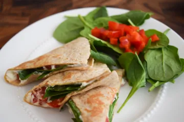 Quesadillas on a plate with spinach and red pepper