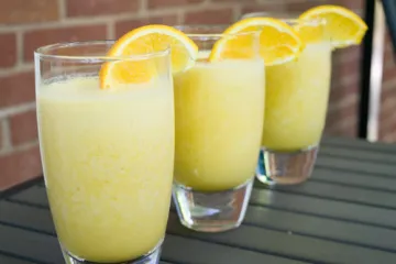 3 orange cow drinks in a row with orange slices