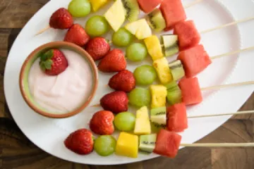 Strawberry, green grapes, pineapple, kiwi, and watermelon on a sticks with fruit dip
