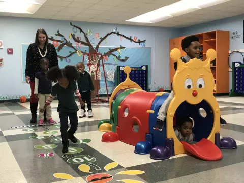 Indoor playground featuring kids playing as a teacher supervises